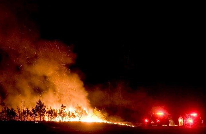 Fire fighters stand in front of the fire, working to bring it down.